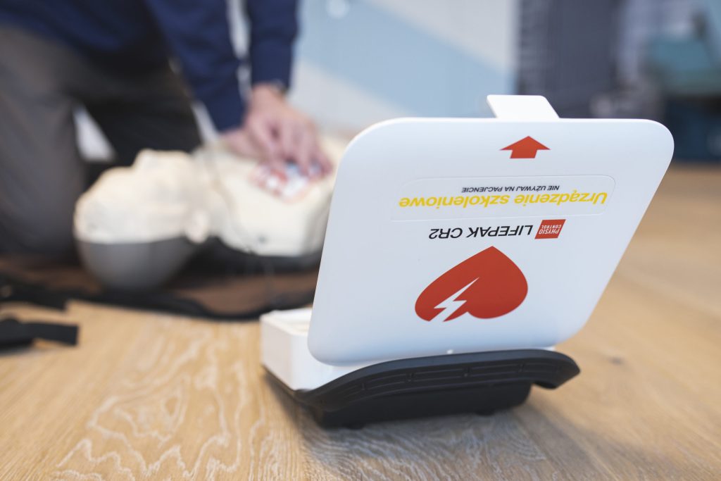 Automatyczny defibrylator AED podczas symulacji udzielania pierwszej pomocy – urządzenie używane do ratowania życia w nagłych przypadkach zatrzymania akcji serca.